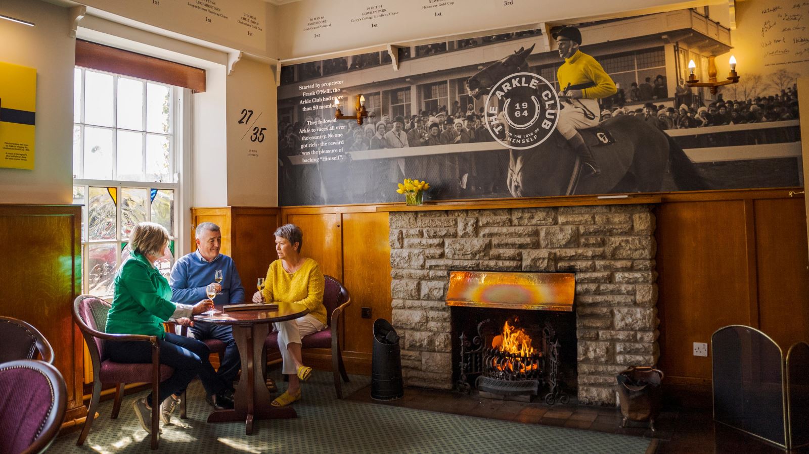 Group of peoplke sitting at a table by the fire enjoying whiskies